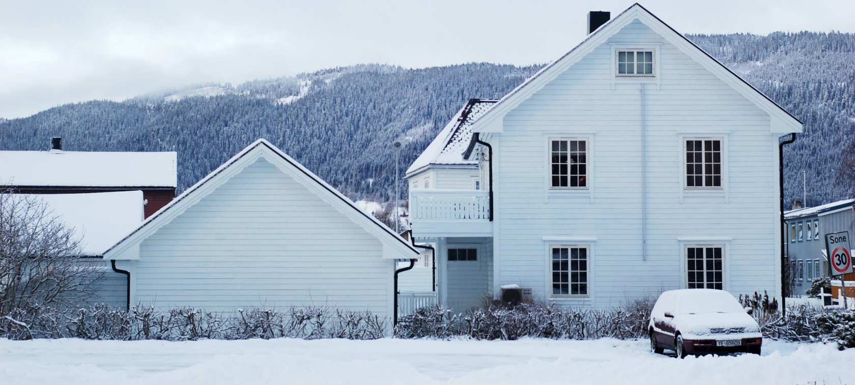 Hvit enebolig på vinteren med snø på taket
