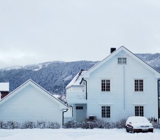 Hvit enebolig på vinteren med snø på taket