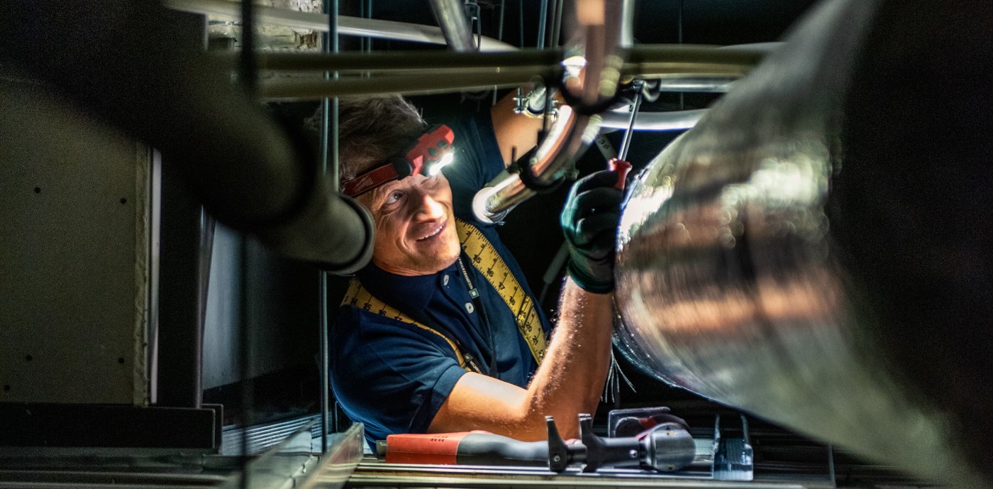 Nærbilde av rørlegger som utfører kontroll på teknisk anlegg med hodelykt