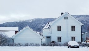 Hvit enebolig på vinteren med snø på taket